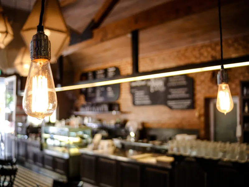 Comptoir d'un café chaleureux avec ampoules suspendues et boiseries.